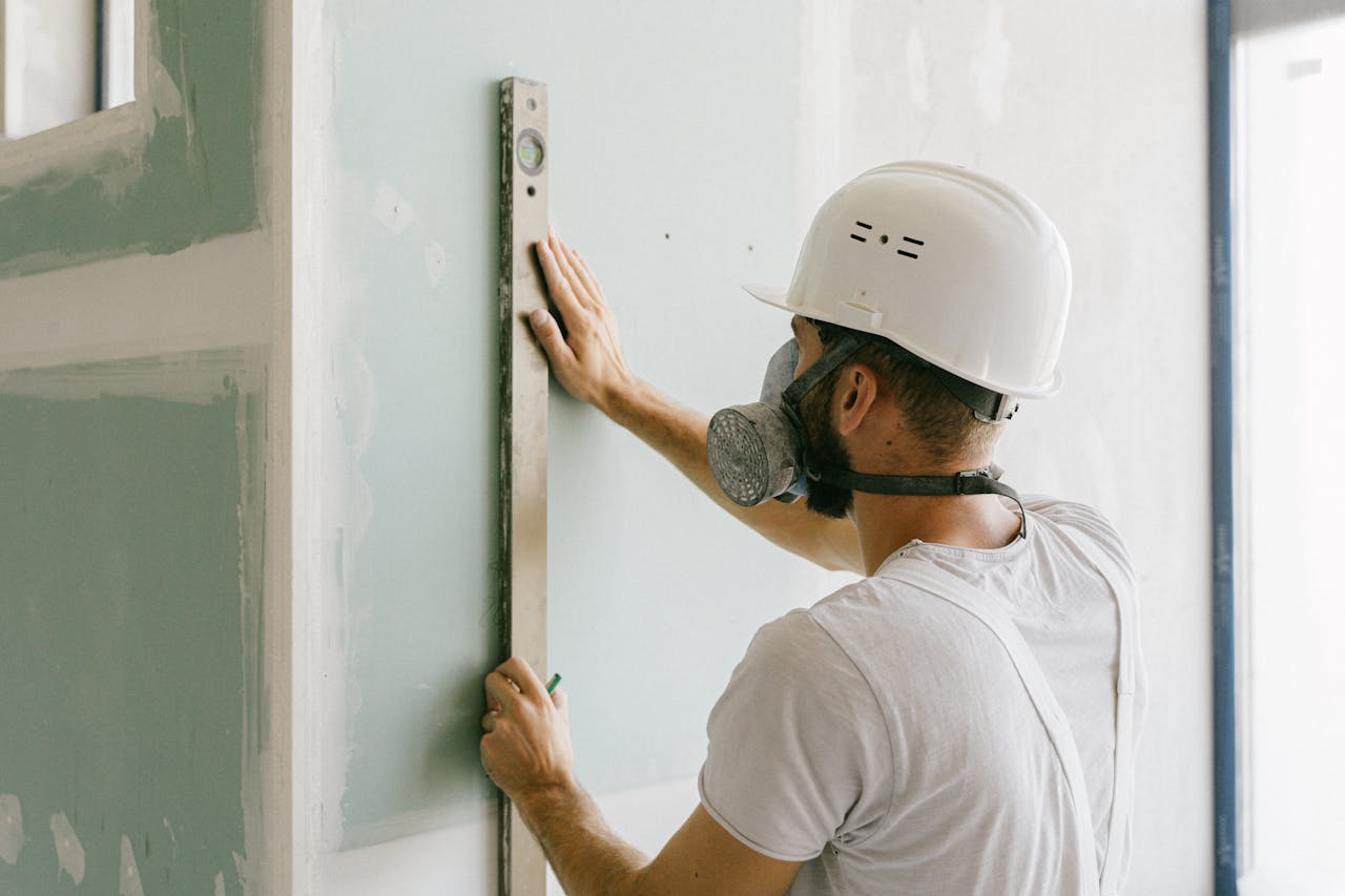 A construction worker using a leveler to ensure wall accuracy, showcasing precision.